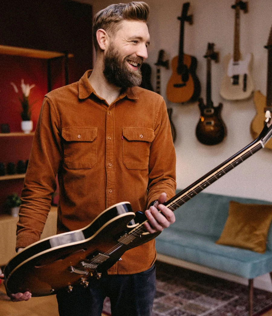 Paul Davids holding his guitar in his studio